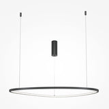 The Glint LED Circular Suspension Light 80cm - Black boasts a minimalist design with a sleek black frame and adjustable ceiling wires. A central cylinder connects its structure, creating a modern aesthetic on a white backdrop.