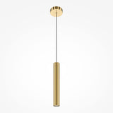 The Pro Focus Thin Pendant Light - Brass features a modern cylindrical gold fixture and a sleek design. Hanging from a black cord with a matching gold ceiling mount, its ideal for minimalist interiors, offering elegant ambient lighting against plain white backdrops.