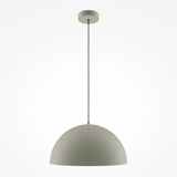 The Basic Colors Dome Pendant Light in grey features a sleek metal shade. Suspended by a dark cord, it exudes elegance against a white backdrop, embodying modern minimalist lighting.