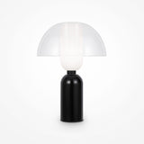 The Memory Table Lamp - Black showcases a black ceramic base and a dome-shaped opal white glass shade. Its minimalist, sleek design effortlessly elevates any rooms decor.