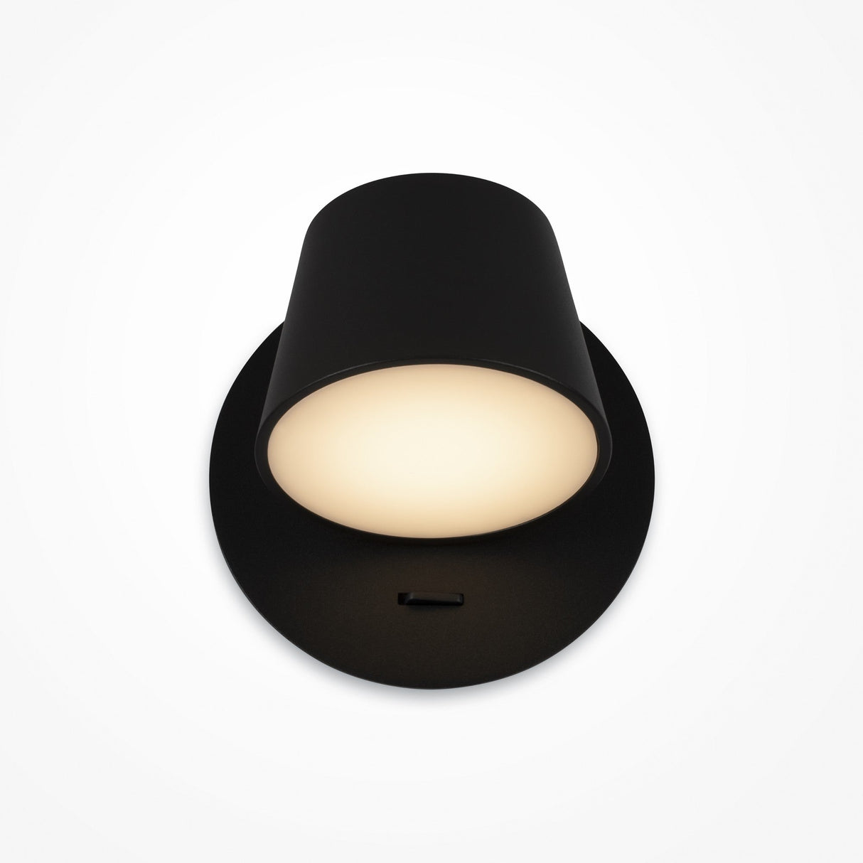 The Pixel LED Wall Light - Black features a cylindrical shade and round base, emits a soft white glow, and is energy-efficient. Mounted against a white background, it offers adjustable lighting to complement any ambiance.