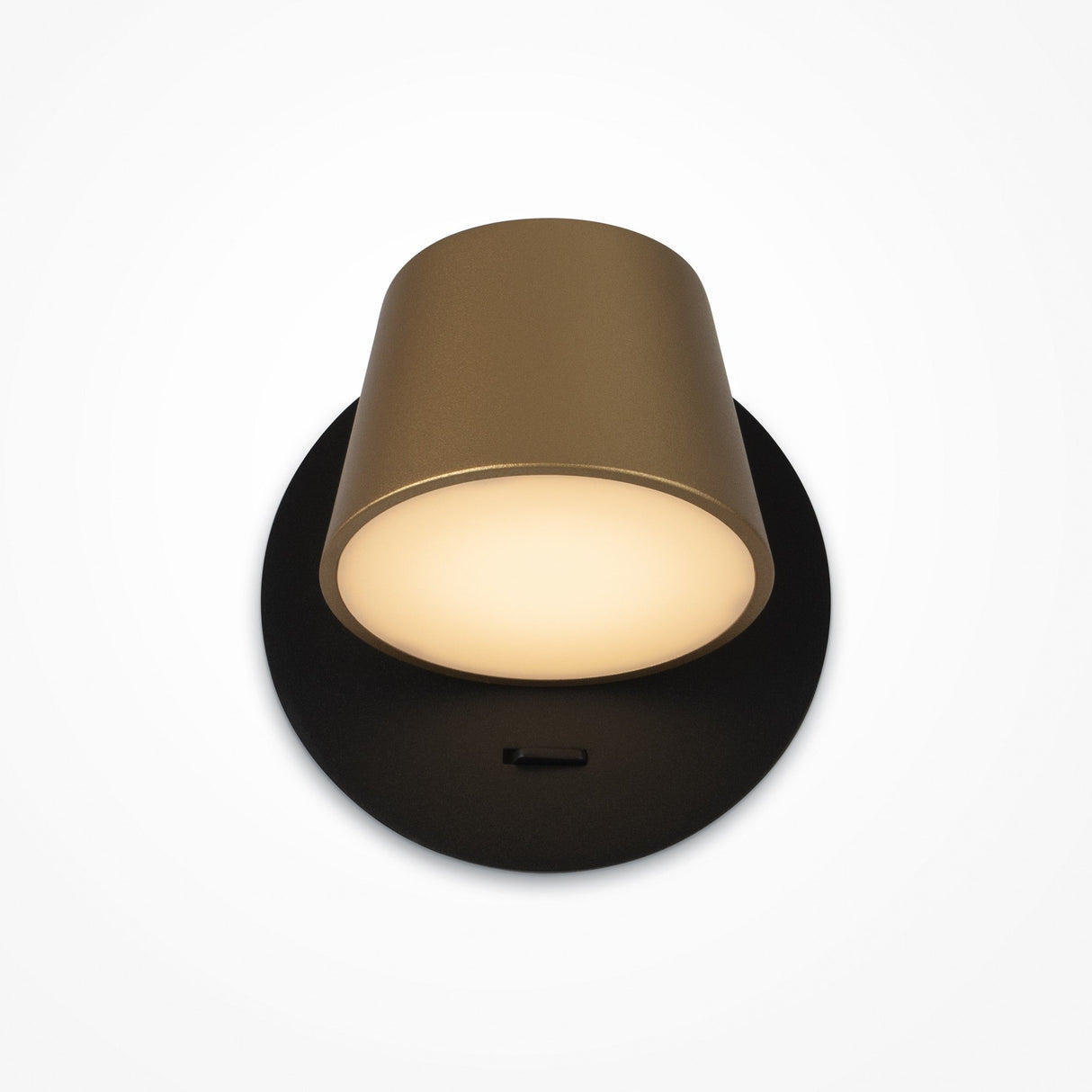 A modern lamp with a cylindrical gold shade and a sleek black & brass circular base. When on, it emits a soft, warm glow with adjustable lighting options. The background is plain white.