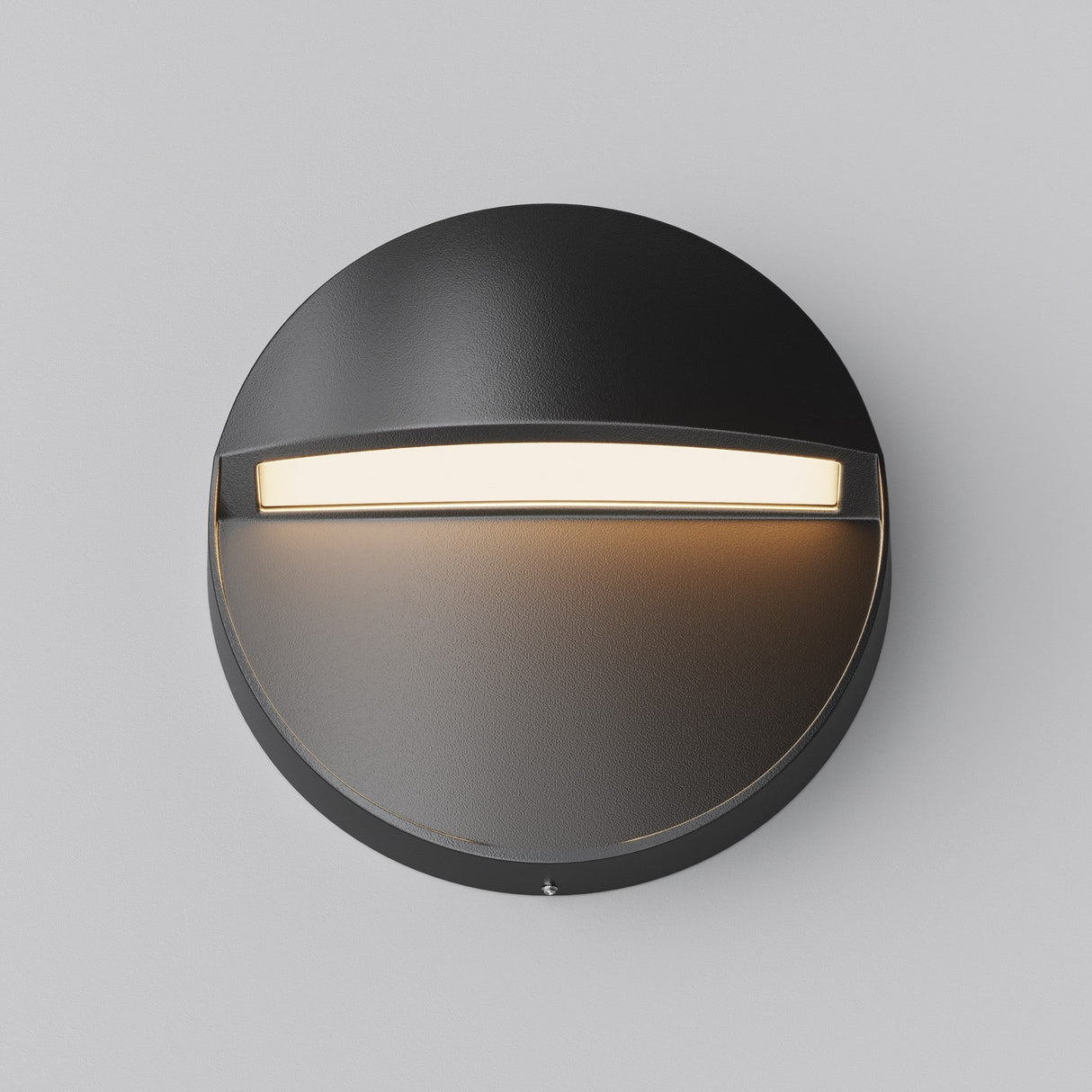 The Mane Outdoor LED Round Wall Light features a black finish and modern design, casting efficient downward light. Its curved top offers a semi-circular glow below, seamlessly blending with the light gray wall for an elegant outdoor illumination.