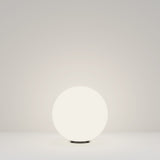 The Erda Pedestal Light 29cm - White casts a gentle glow on a plain, light surface against a matching background. Its weather-resistant design is ideal for fostering a minimalist and serene ambiance in both indoor and outdoor settings.