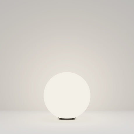 The Erda Pedestal Light 29cm - White casts a gentle glow on a plain, light surface against a matching background. Its weather-resistant design is ideal for fostering a minimalist and serene ambiance in both indoor and outdoor settings.