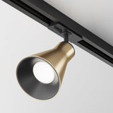 The Virar Single Phase Unity Track Spotlight in matte gold features a swivel mechanism and mounts on a black rail against a white ceiling. Its conical design directs light downward, offering sleek accent lighting with a minimalist aesthetic.