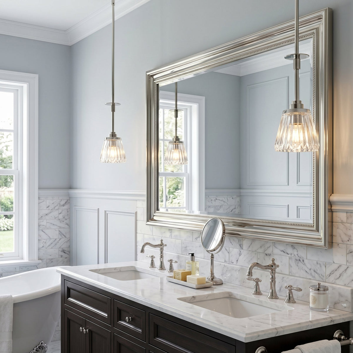 Elstead Lighting Agatha polished chrome pendant lights with faceted cut glass shades above a marble vanity with twin sinks in a pale blue bathroom.