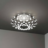 The Mesh LED Ceiling Light - Black features a circular open-grid design with multiple small white bulbs in a honeycomb pattern, casting an ambient glow—ideal for modern interiors and easily mounted on any gray ceiling.