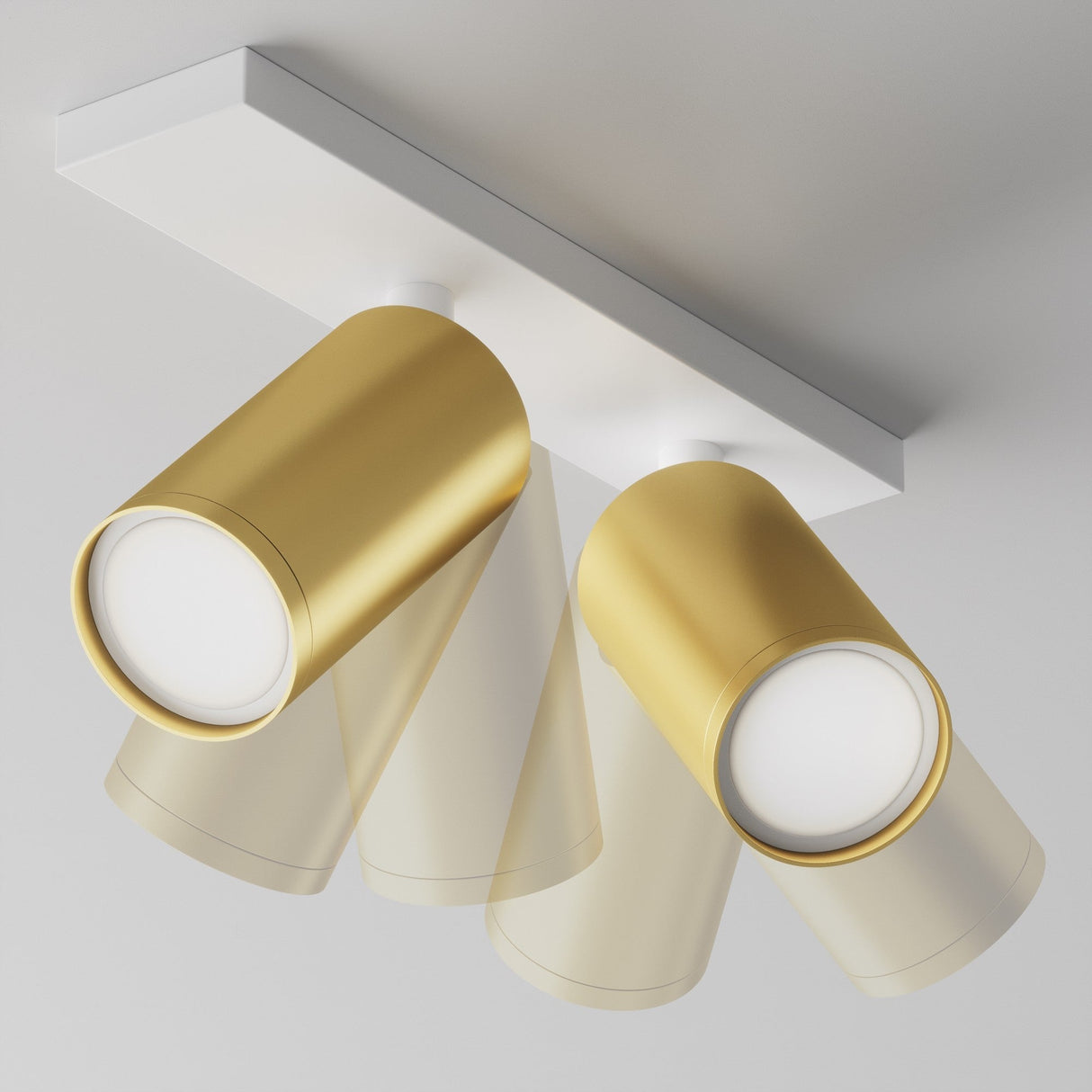 A close-up view of the Focus S Twin Bar Spotlight, featuring two adjustable cylindrical spotlights in matte gold on a white rectangular base. The sleek design complements minimalistic and contemporary interiors against a plain white ceiling.