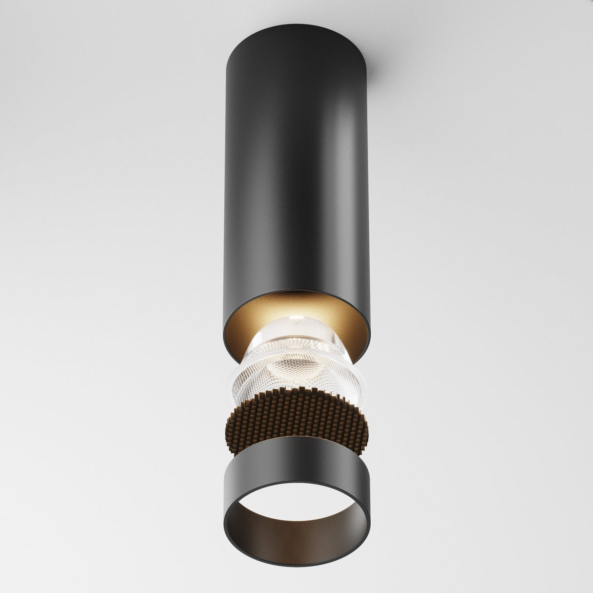 The Focus LED Fixed Round Surface Mounted Downlight 12W 3000K in black features a modern cylindrical design with a suspended inner bulb and decorative accents on a white background, offering an energy-efficient option for sleek contemporary lighting solutions.