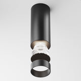 The Focus LED Dimmable Fixed Round Downlight 12W 4000K in black is a modern cylindrical surface-mounted light on a plain white ceiling. It features a transparent middle section revealing internal components, and a black ring at the base, enhancing its dimmable lighting capabilities.
