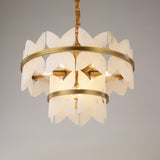 Niori Petraia two-tier chandelier with sculpted white alabaster petals arranged around brushed brass rings, suspended from a brass chain on a grey background.