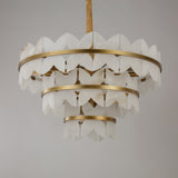Niori Petraia three-tier chandelier with scalloped alabaster petals arranged around brushed brass rings, suspended from a fabric-covered chain.