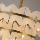 Close-up of Niori Petraia chandelier showing scalloped alabaster petals arranged around brushed brass tiered rings with warm inner lighting.
