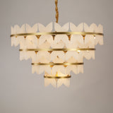 Niori Petraia four-tier chandelier featuring sculpted alabaster petals around brushed brass rings, suspended from a rope-wrapped drop against a grey background.