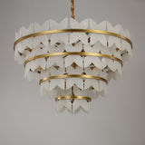 Niori Petraia four-tier chandelier with alabaster floral petals on brushed brass rings, suspended from a rope-wrapped drop against a light background.