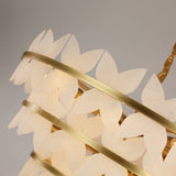 Close-up of the Niori Petraia floral chandelier showing tiered brushed brass rings supporting layered white alabaster petals.
