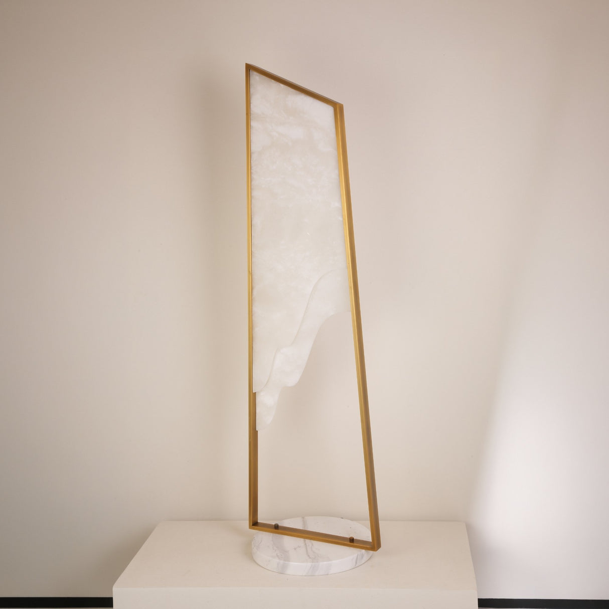 Niori Atria Small LED alabaster floor lamp with tapered brushed brass frame and circular white marble base against a neutral background.
