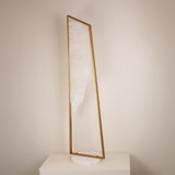 Niori Atria Large alabaster floor lamp with tapered brushed brass frame and circular white marble base, displayed on a plinth against a neutral wall.