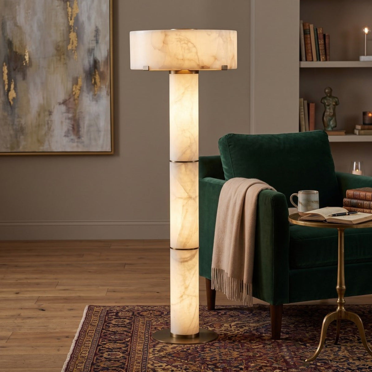 Colonnetta 3 Light Column Alabaster Floor Lamp with brushed brass collars and base disc, glowing beside a green armchair in a living room setting.