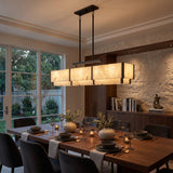 Quadrena Linear Alabaster Chandelier 113cm in matt black, glowing rectangular alabaster panels with black uprights, shown above a dining table in a modern dining room.