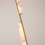 Close-up of Niori Selvara LED vertical duo pendant light showing staggered natural alabaster bars on a brushed brass stem, illuminated with warm white light.