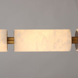 Close-up of the Ardent LED alabaster column pendant light, showing natural stone cylinders joined by brushed brass spacers, glowing warm white against a plain grey background.