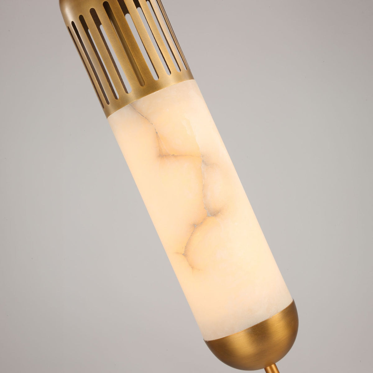 Close-up of the Zerith LED alabaster tube pendant light with fluted brushed brass collar and domed brass base cap, on a plain light grey background.