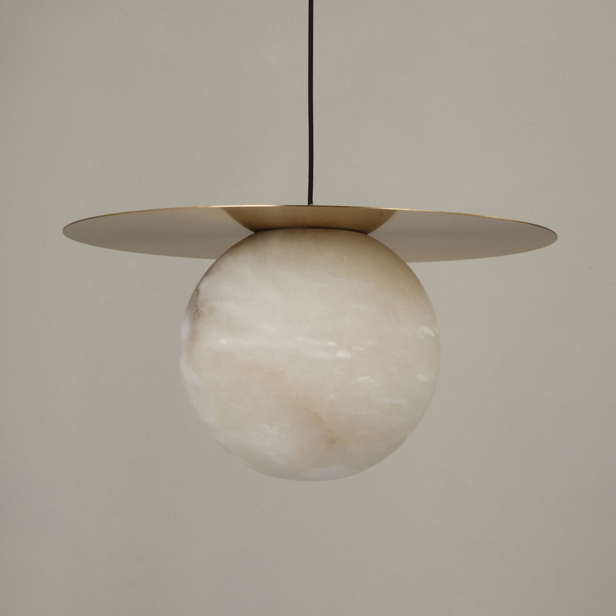 Marenzo Alabaster Orb Pendant Light in Brushed Brass, featuring a natural alabaster sphere beneath a flat brass reflector disc, shown against a plain light background.