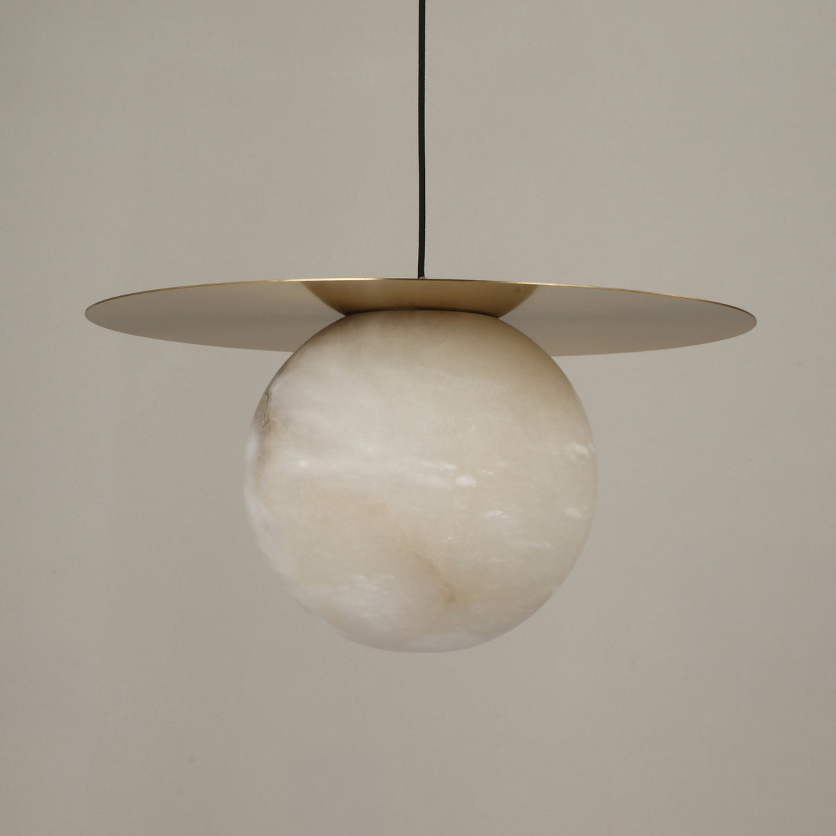 Marenzo Small Orb Alabaster Pendant Light in brushed brass, featuring a spherical alabaster shade beneath a flat circular brass disc, shown against a plain light background.