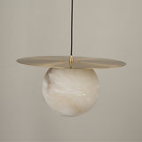 Marenzo Alabaster Orb Pendant Light in Brushed Brass, showing a natural alabaster sphere beneath a flat brass disc reflector, on a plain light background.