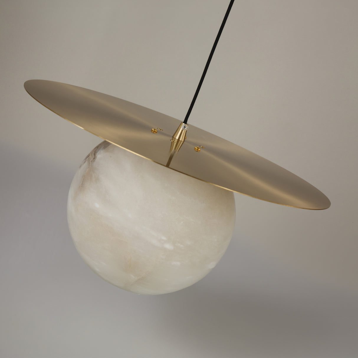 Marenzo Small Orb Alabaster Pendant Light in Brushed Brass, featuring a spherical alabaster shade beneath a flat round brass disc on a slim stem, shown against a plain light grey background.