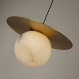 Marenzo Small Orb Alabaster Pendant Light in Brushed Brass, featuring a round alabaster sphere beneath a flat brass disc shade, shown against a plain grey background.