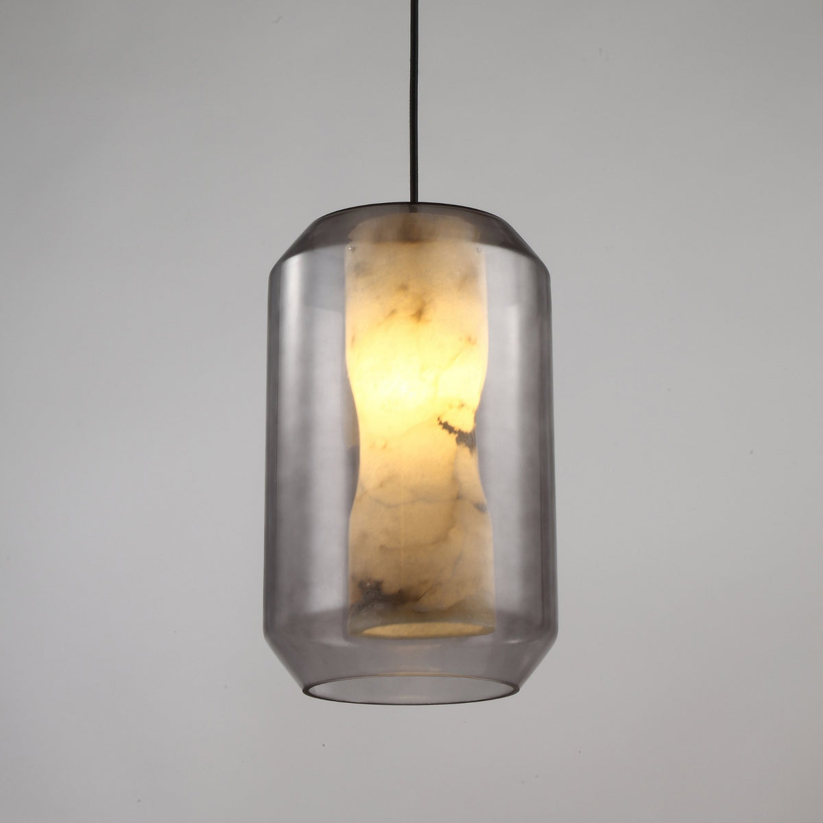 Vale Faceted Alabaster Pendant Light in Soft White, a lantern-shaped fixture with a glowing alabaster column inside faceted clear glass, black flex cord, shown on a plain grey background.