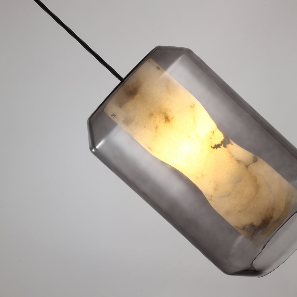 Niori Vale Faceted Alabaster Pendant Light in Soft White, angled view showing the natural stone core glowing within a clear faceted glass shell.