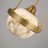Close-up of the Calis single pendant light, a spherical alabaster globe wrapped in a brushed brass band with brass stem, on a plain grey background.