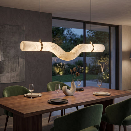 Zareon LED Medium Curved Alabaster Chandelier with brushed brass collars, illuminated above a wooden dining table with green chairs in a modern dining room.
