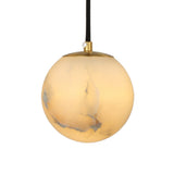 Lyvane globe pendant light in natural alabaster with a brushed brass ceiling cap and black flex, glowing warm white against a plain background.