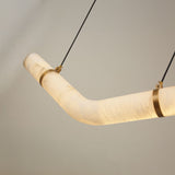 Zareon Small LED Chevron Alabaster Chandelier with angled boomerang profile, brushed brass cuffs at the bend, and twin black suspension cables against a plain grey background.