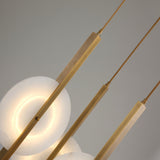 Close-up of Niori Elyra 3 Light LED Alabaster Cluster Chandelier with brushed brass blade stems, suspension cables, and a warm-lit translucent alabaster disc.
