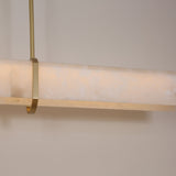 Close-up of Niori Zarune LED linear chandelier showing the alabaster bar with natural veining, brushed brass ring bracket and slim drop rod.