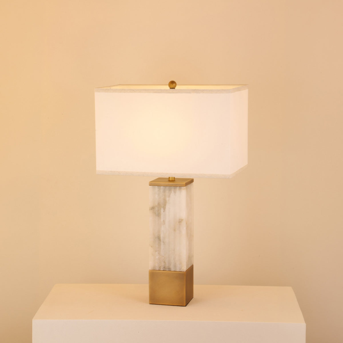 Ravelle Alabaster Column Table Lamp with fluted stone base, brushed brass accents, and rectangular soft white fabric shade.