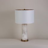 Calynor 1 Light Column Alabaster Table Lamp with brushed brass base and stem, topped with a white drum shade, shown against a plain neutral background.