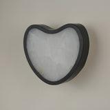 Niori Marea LED wall light with matte black copper frame wrapping a teardrop-shaped natural Spanish alabaster panel, shown against a pale wall.