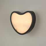 Niori Marea LED wall light in matte black with a teardrop-shaped natural alabaster panel set in a curved copper frame, shown lit against a light grey wall.