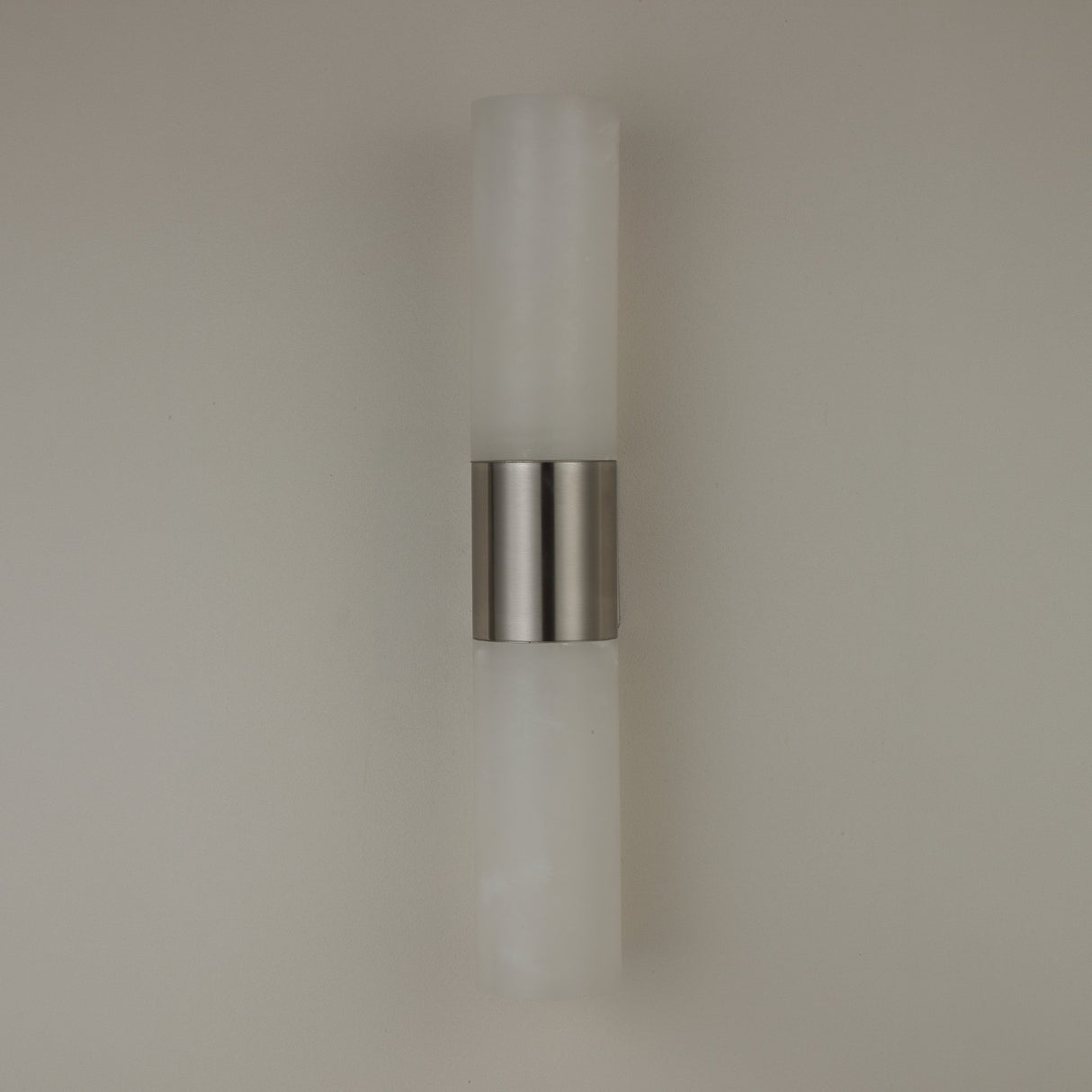 Niori Fiora LED wall light with two vertical Spanish alabaster columns joined by a satin nickel band, mounted on a plain neutral wall.