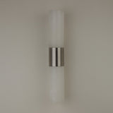 Niori Fiora LED wall light with two vertical Spanish alabaster columns joined by a satin nickel band, mounted on a plain neutral wall.