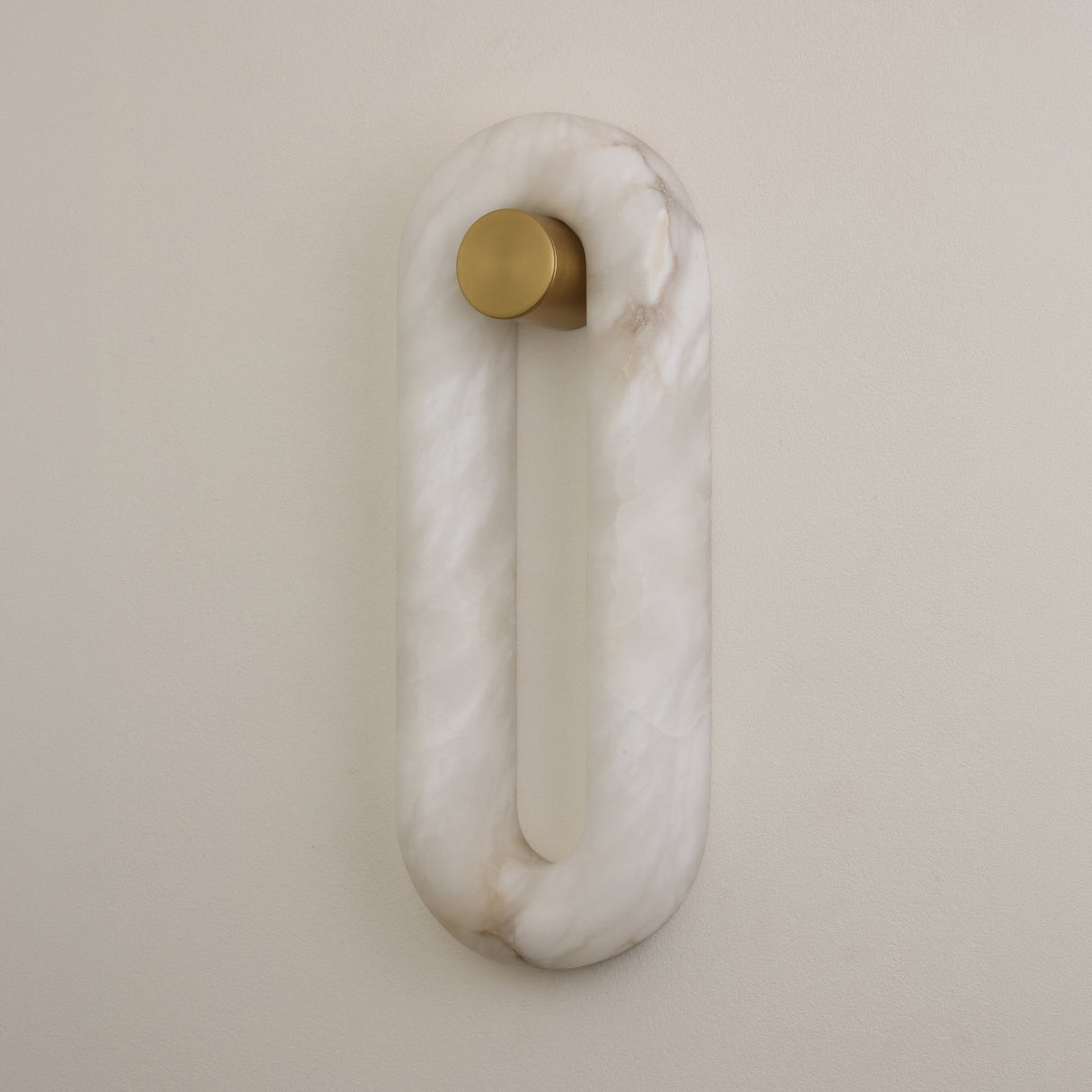 Niori Serava large alabaster wall light with an elongated oval ring in soft white Spanish alabaster, mounted on a brushed brass cylindrical bracket.