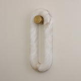 Serava LED Small Alabaster Wall Light in soft white, oval ring shape with natural alabaster veining and a brushed brass cylindrical fixing, mounted on a plain light wall.