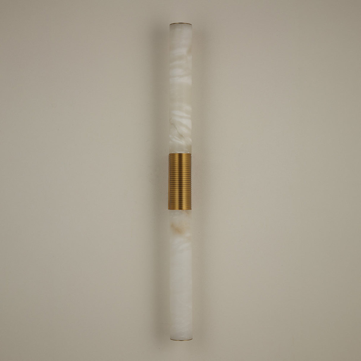 Niori Eryon LED large wall light with two natural Spanish alabaster cylinders joined by a ribbed brushed brass mount, mounted on a pale wall.